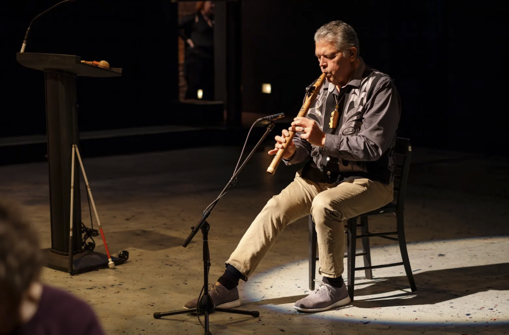 Native American man playing a traditional flute